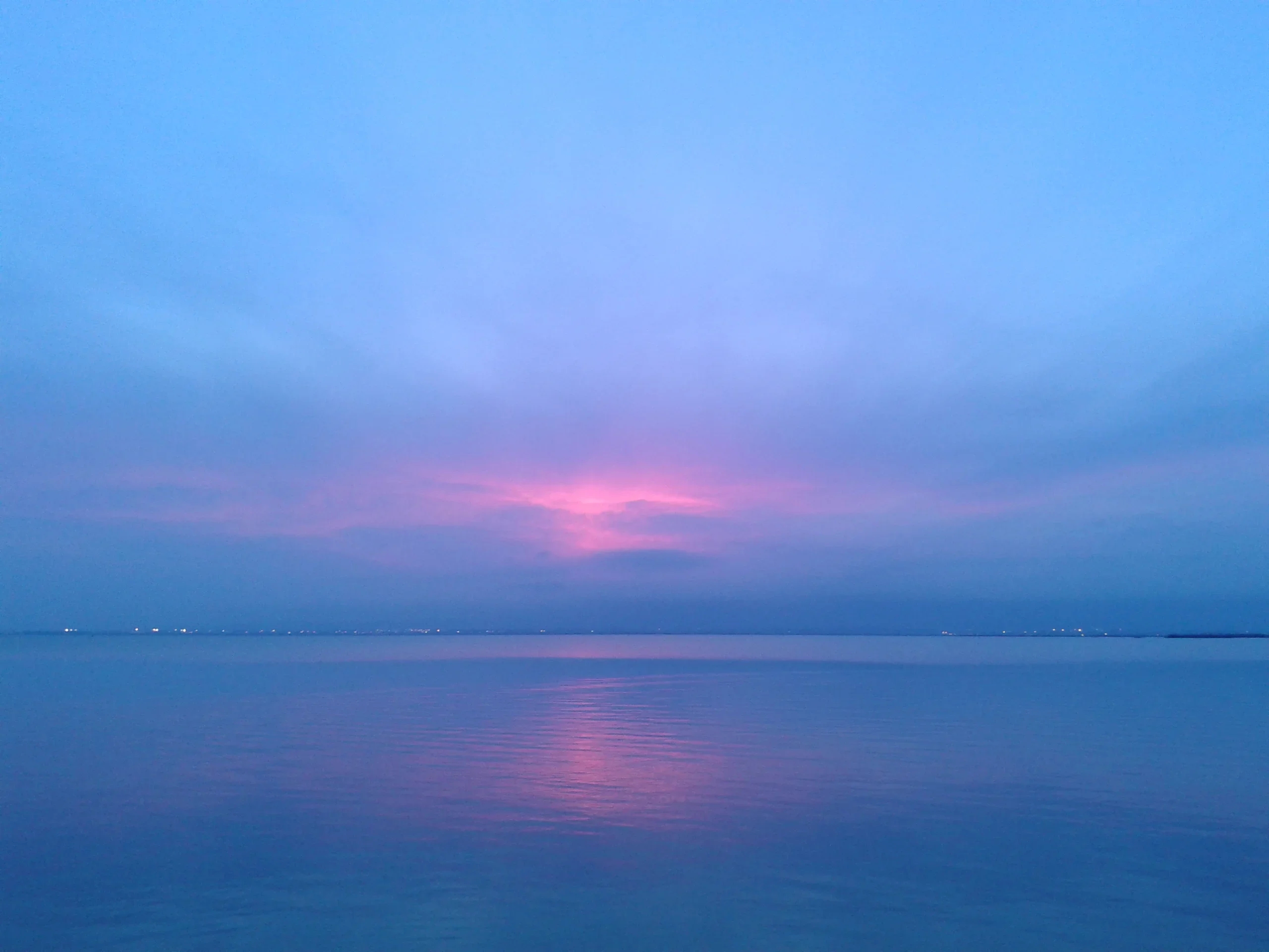 Закат над озером Альбуфера: розово-золотое небо, тёмные силуэты тростника и плоской лодки на воде