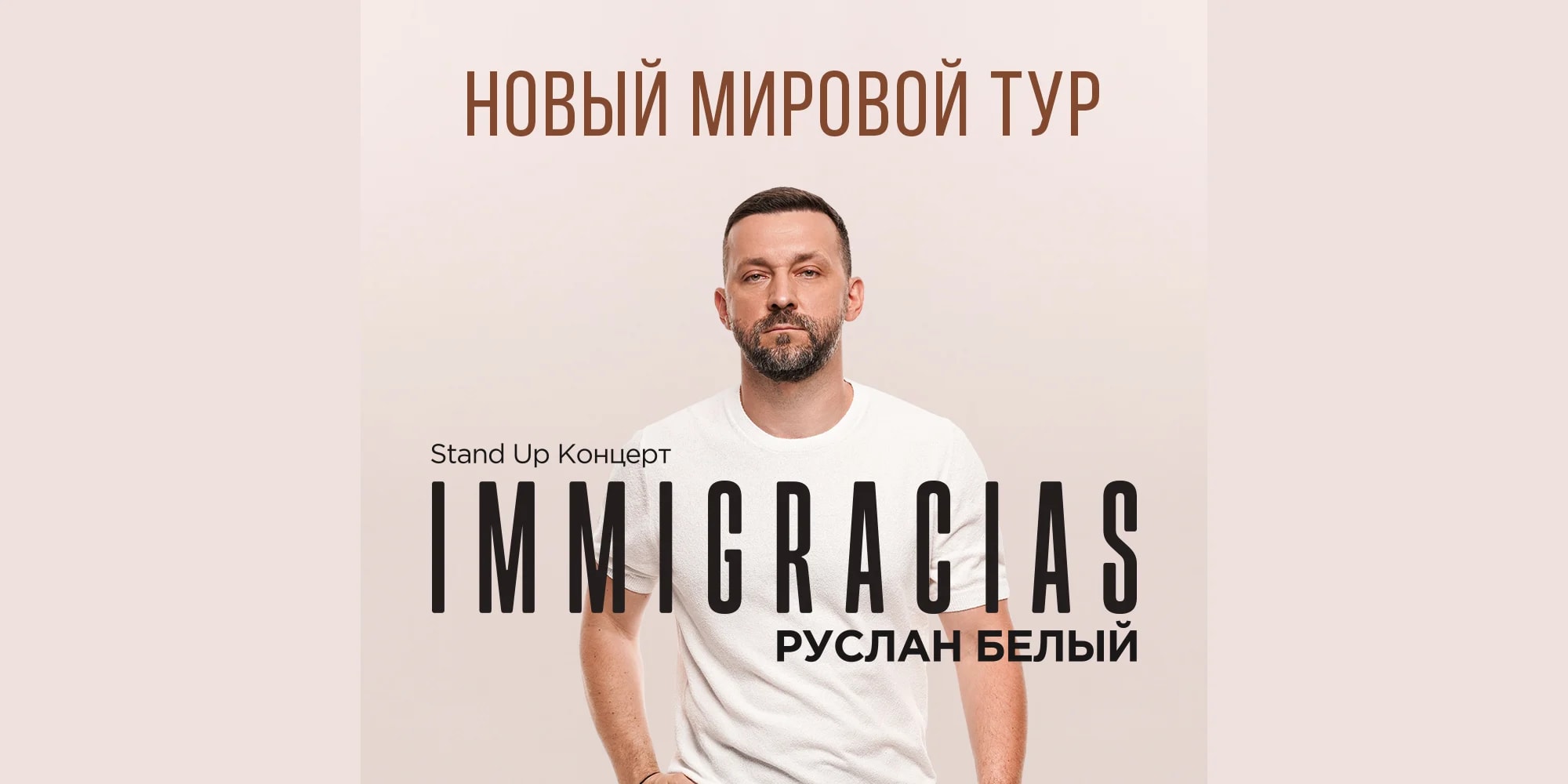 Афиша мирового тура Руслана Белого «IMMIGRACIAS»: фотография комика в белой футболке на светлом фоне с надписью «Новый мировой тур · Stand Up Концерт · IMMIGRACIAS · Руслан Белый»