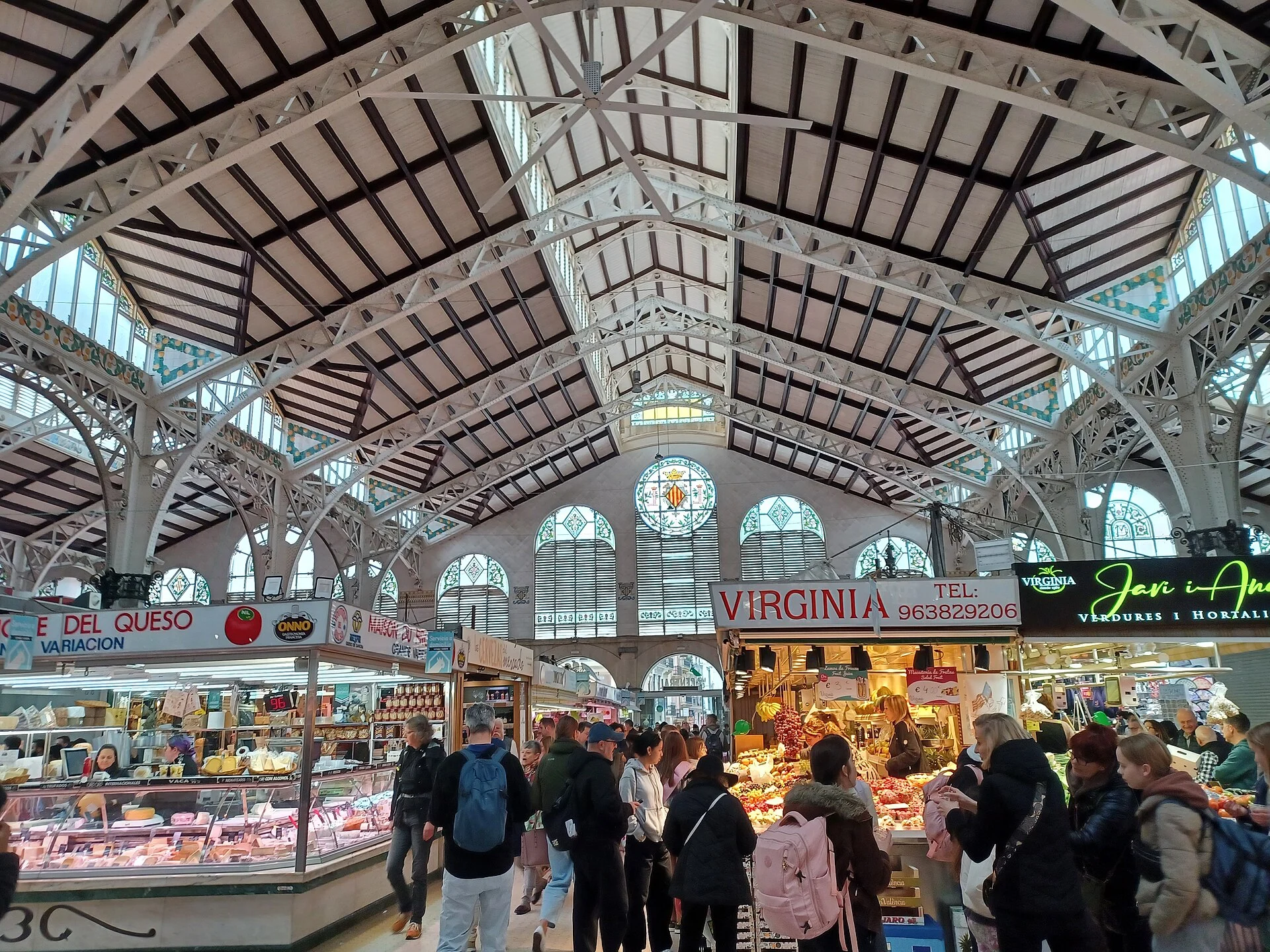 Парады Mercat Central под арочными витражами: мясная парада, овощи и фрукты, покупатели в утренние часы